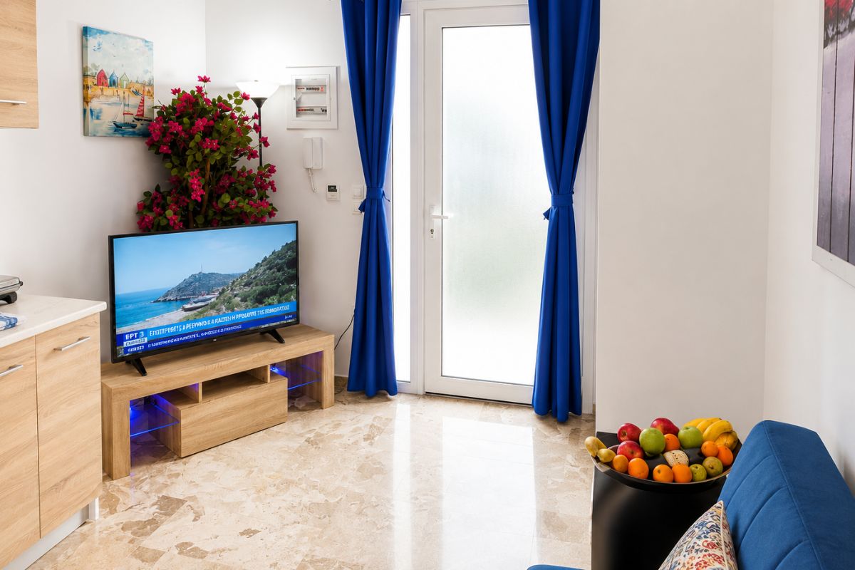 Φωτεινός χώρος καθιστικού στο Patras Blue Suite με καναπέ, τηλεόραση, φυσικό φωτισμό και άμεση πρόσβαση στον ιδιωτικό κήπο