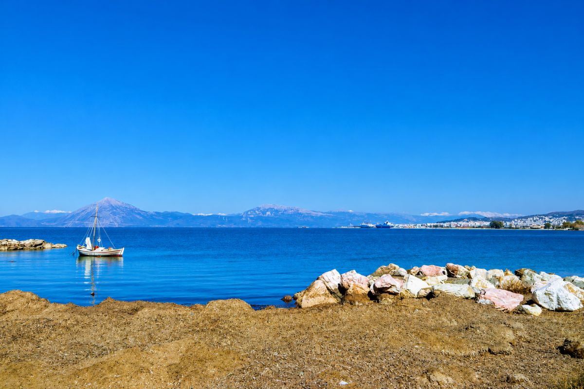 Πανοραμική θέα στον Πατραϊκό Κόλπο με ιστιοπλοϊκό, καταγάλανα νερά και φόντο την πόλη της Πάτρας