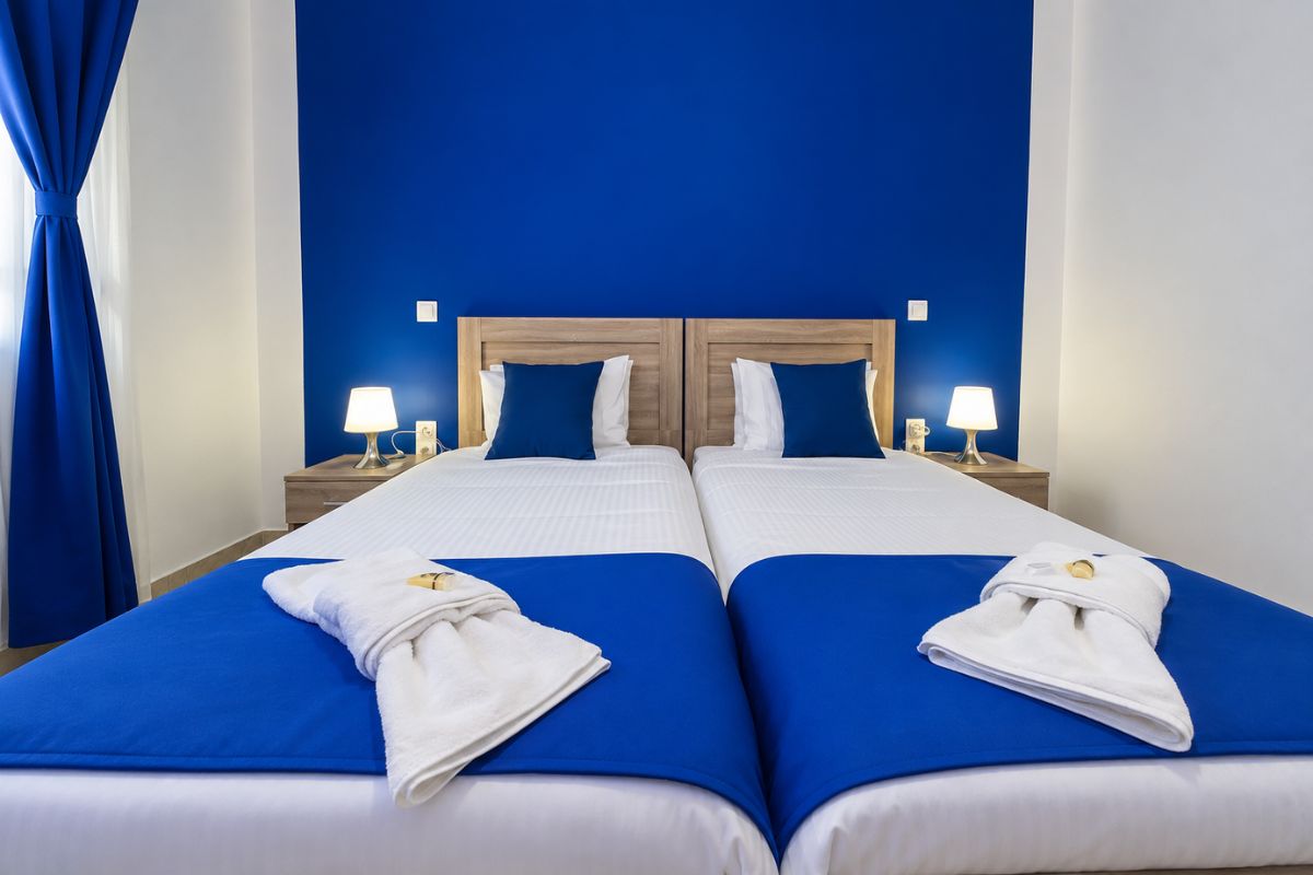 Άνετο υπνοδωμάτιο στο Patras Blue Suite με δύο μονά κρεβάτια, μοντέρνα διακόσμηση σε μπλε αποχρώσεις, κομοδίνα και φωτιστικά