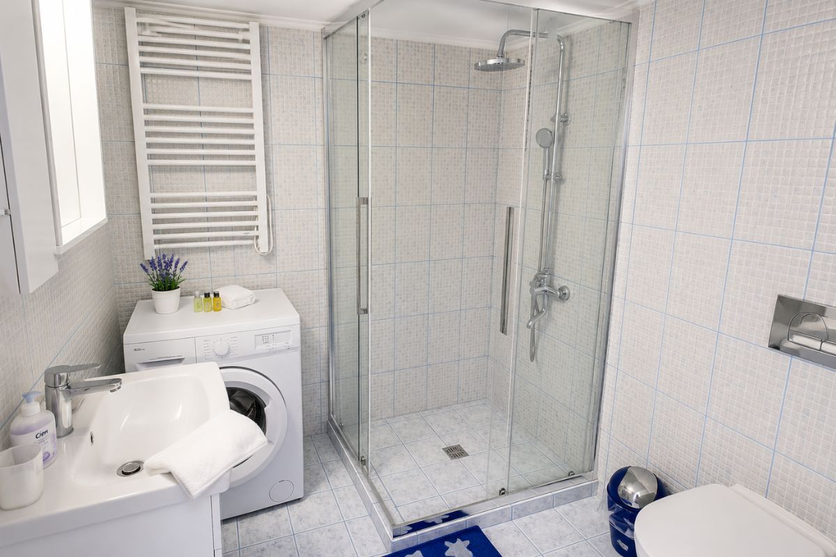 Μοντέρνο μπάνιο στο Patras Blue Suite με ευρύχωρη καμπίνα ντους, πλυντήριο ρούχων, πετσετοκρεμάστρα και πλήρεις παροχές