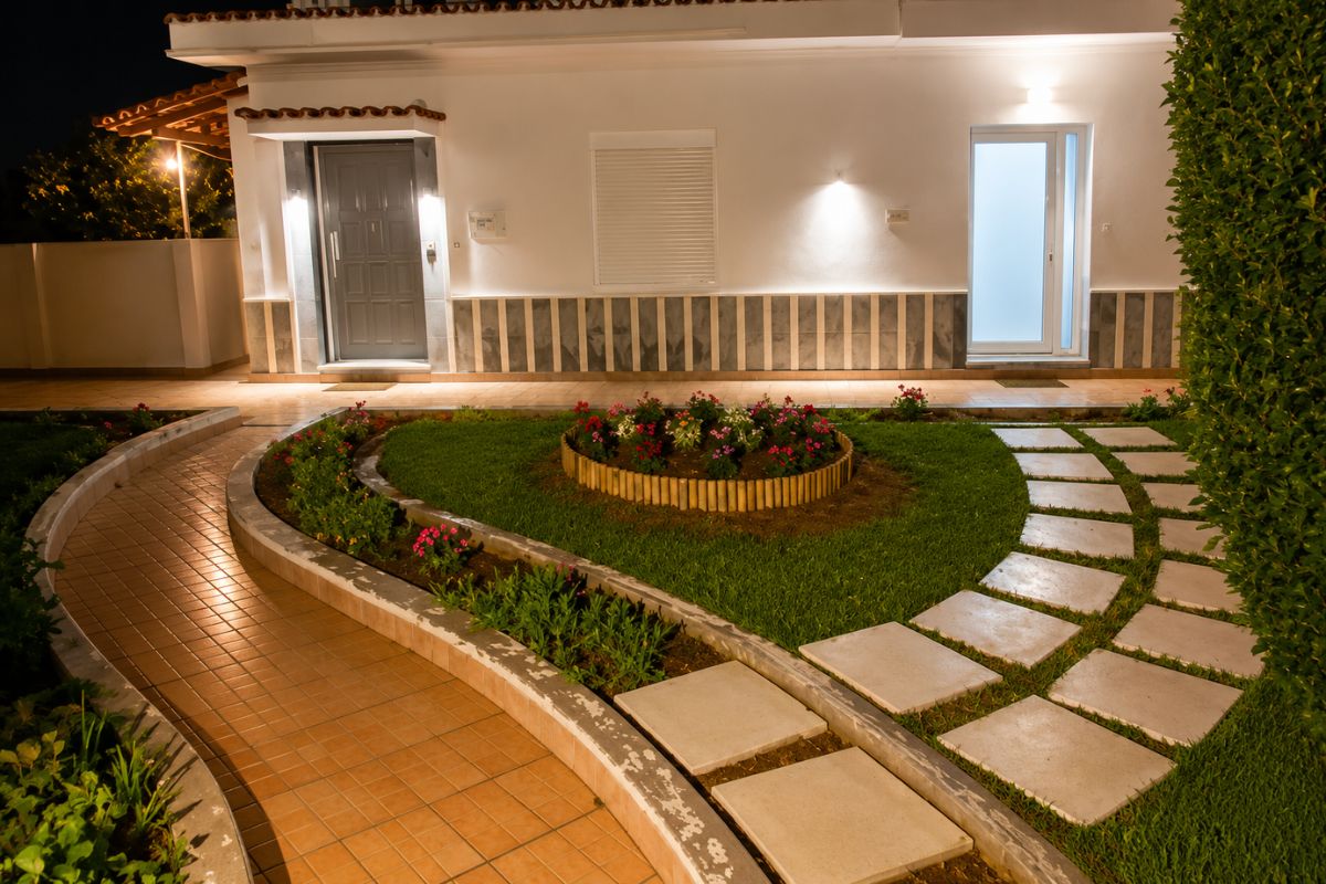 Νυχτερινή άποψη του Patras Golden Suite με φωτισμένο κήπο και κομψή είσοδο