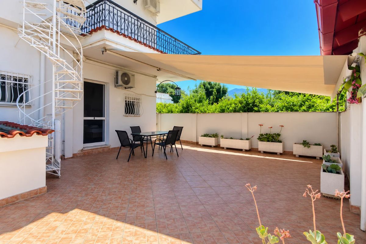 Golden Suite στην Πάτρα – εξωτερική βεράντα με τραπεζαρία και θέα στο πράσινο